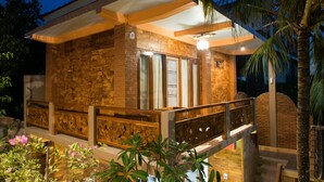 A modern house with a stone facade, large windows, and a balcony with a railing. - Bulan Bali Homestay (Ubud)