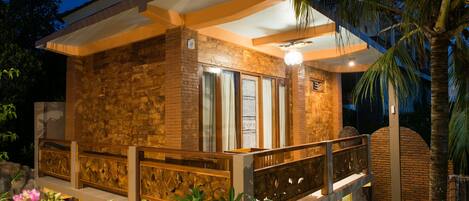 Una casa moderna con fachada de piedra, ventanas grandes y un balcón con barandilla.