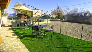 An outdoor patio with artificial green turf, metal chairs, and tables. - Bonne Nuit Guest House (Azzano San Paolo)