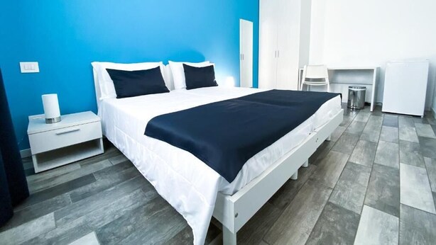 A modern bedroom with a bed, bedside table, and a small desk area. - Bonne Nuit Guest House (Azzano San Paolo)