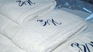 Folded white towels with embroidered initials. - Bonne Nuit Guest House (Azzano San Paolo)
