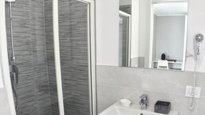 A modern bathroom with a glass-enclosed shower, a white sink, and a mirror above the sink. - Bonne Nuit Guest House (Azzano San Paolo)
