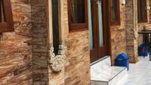 A hallway with stone walls and a wooden door. - Bulan Bali Guest House (Ubud)