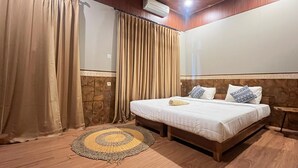 A bedroom with a bed, curtains, a wall-mounted air conditioner, and a wooden floor. - Bulan Bali Guest House (Ubud)