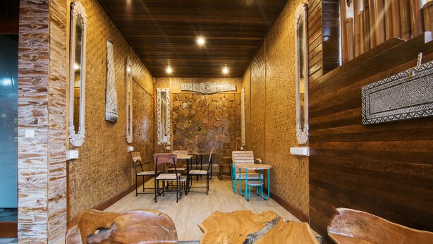 A wooden interior with stone walls, a stone fireplace, and a wooden table with chairs. - Bulan Bali Guest House (Ubud)