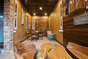 A wooden interior with stone walls, a stone fireplace, and a wooden table with chairs. - Bulan Bali Guest House (Ubud)