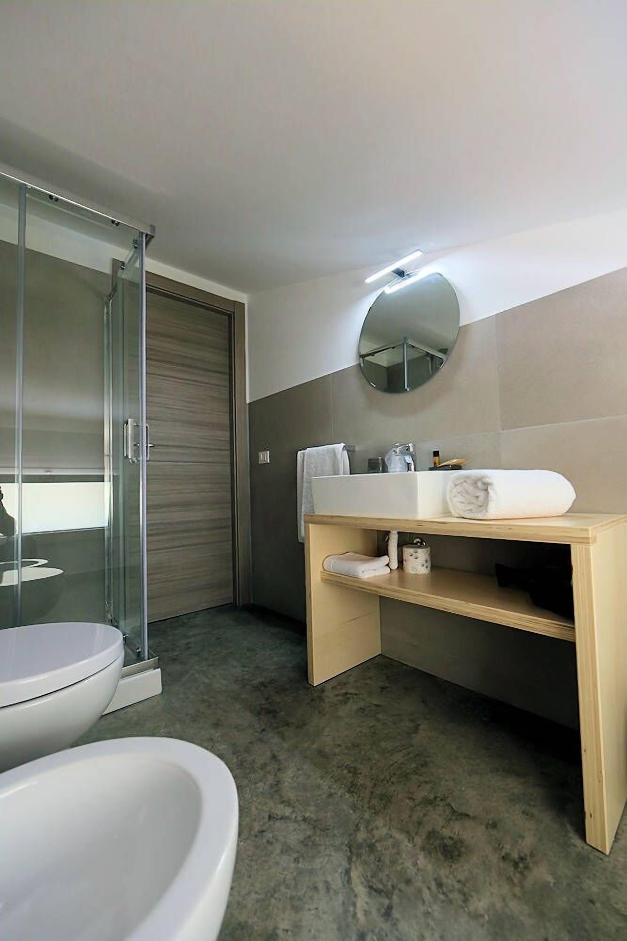 A modern bathroom with a glass shower enclosure, a white sink, and a mirror.