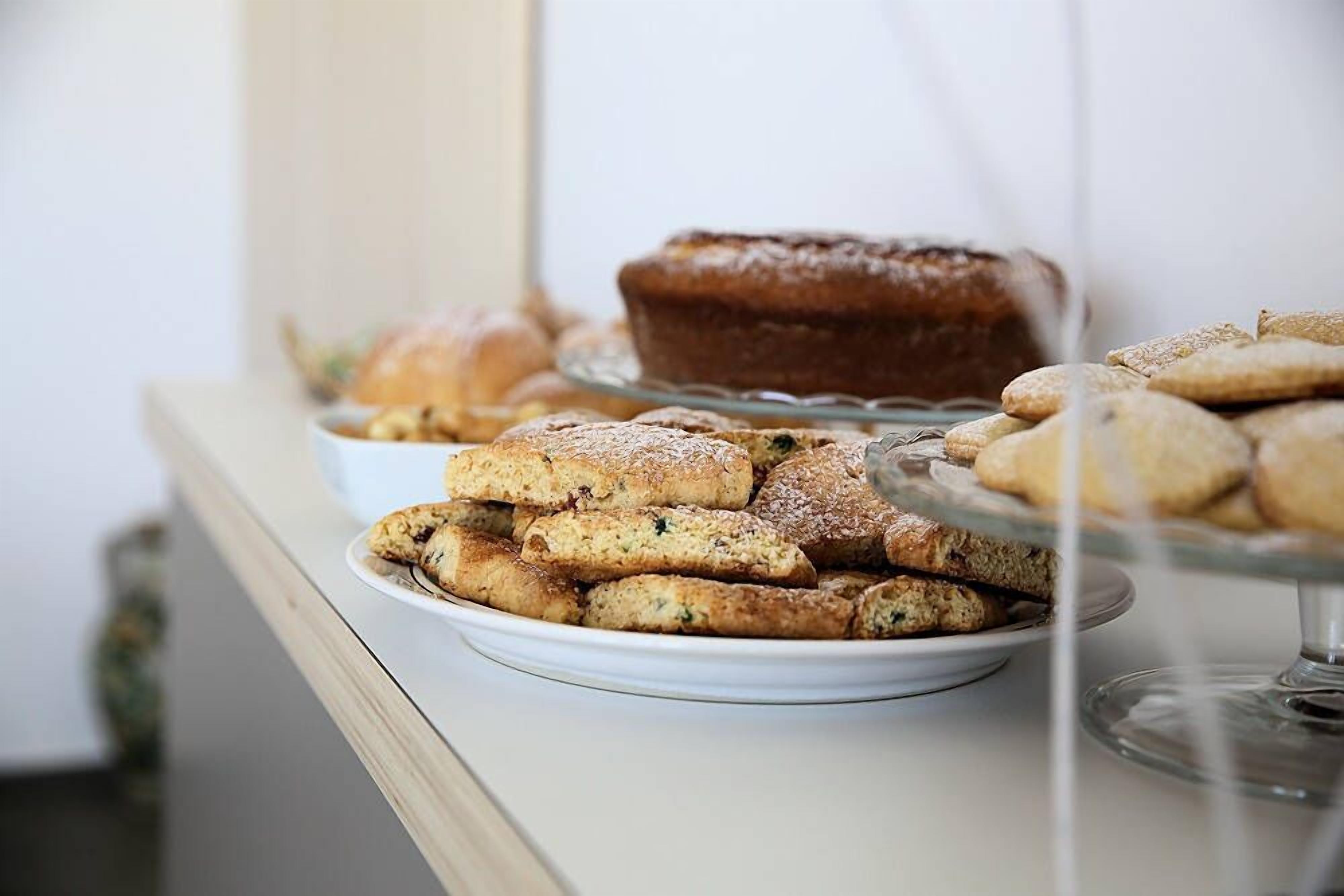 Une table de buffet proposant diverses pâtisseries, notamment des viennoiseries et un gâteau présenté sur un présentoir en verre.