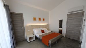 Una habitación de hotel moderna con cama, mesitas de noche, un espejo y un armario.