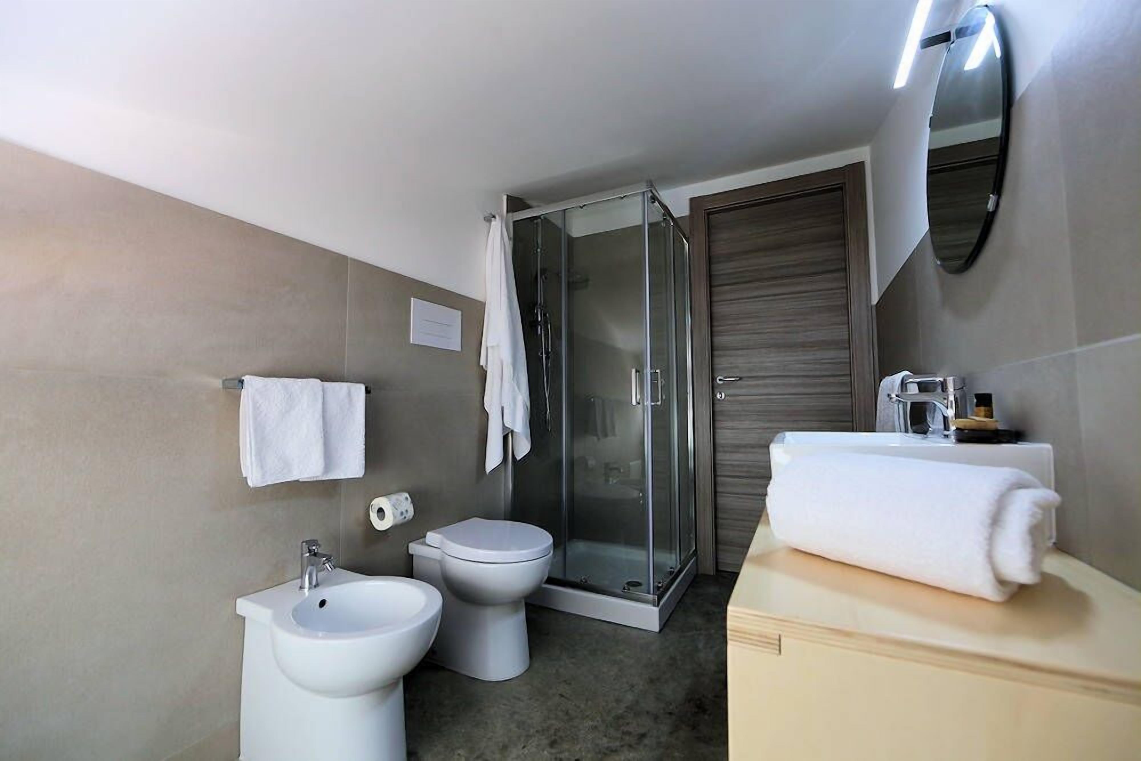Casa de banho moderna com chuveiro, sanita, bidé e lavatório.