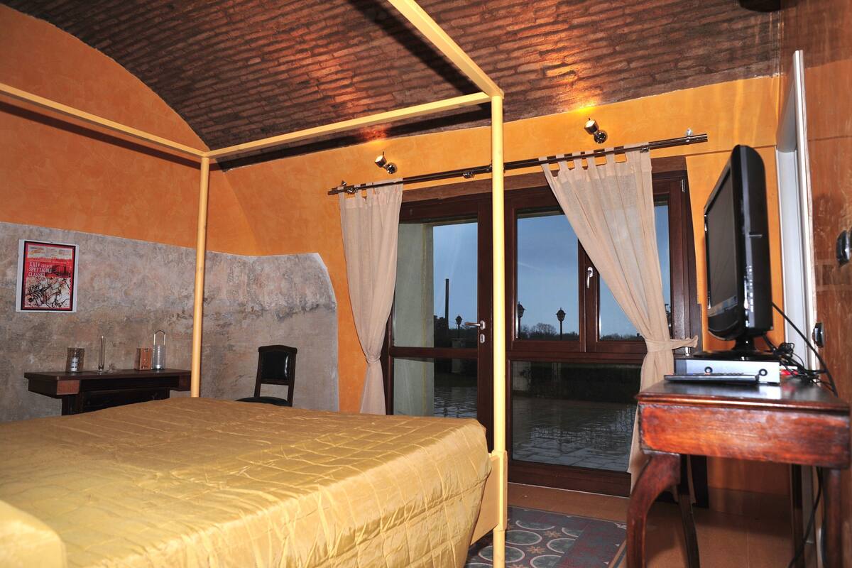 A room with a bed, a desk, a television, and a view of the outside.