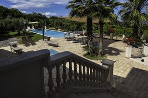 A pool area with lounge chairs, a staircase, and a view of the surrounding landscape. - Tenuta Santa Tecla (Acireale)