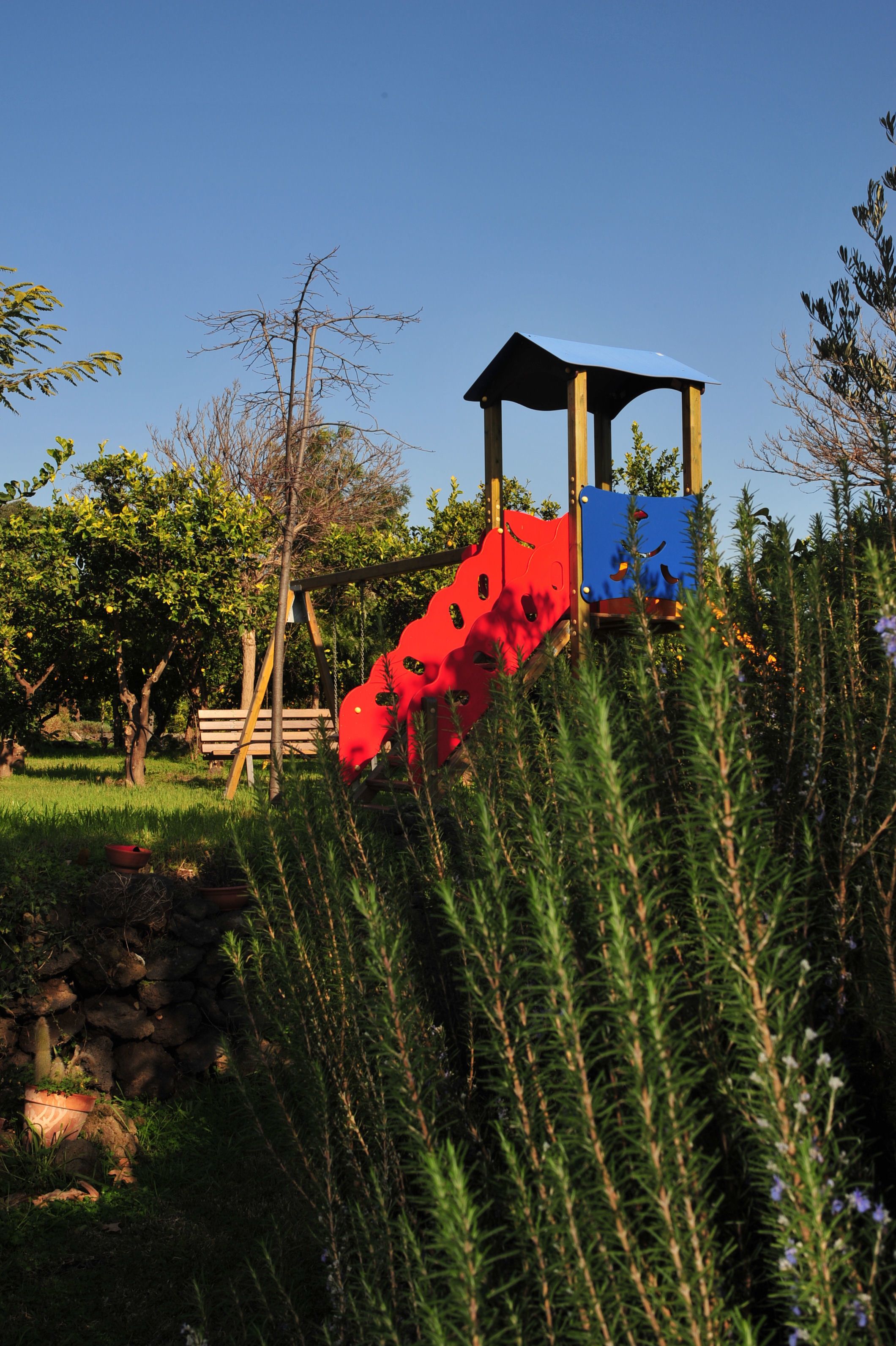 A playground with a red slide and a blue climbing structure.