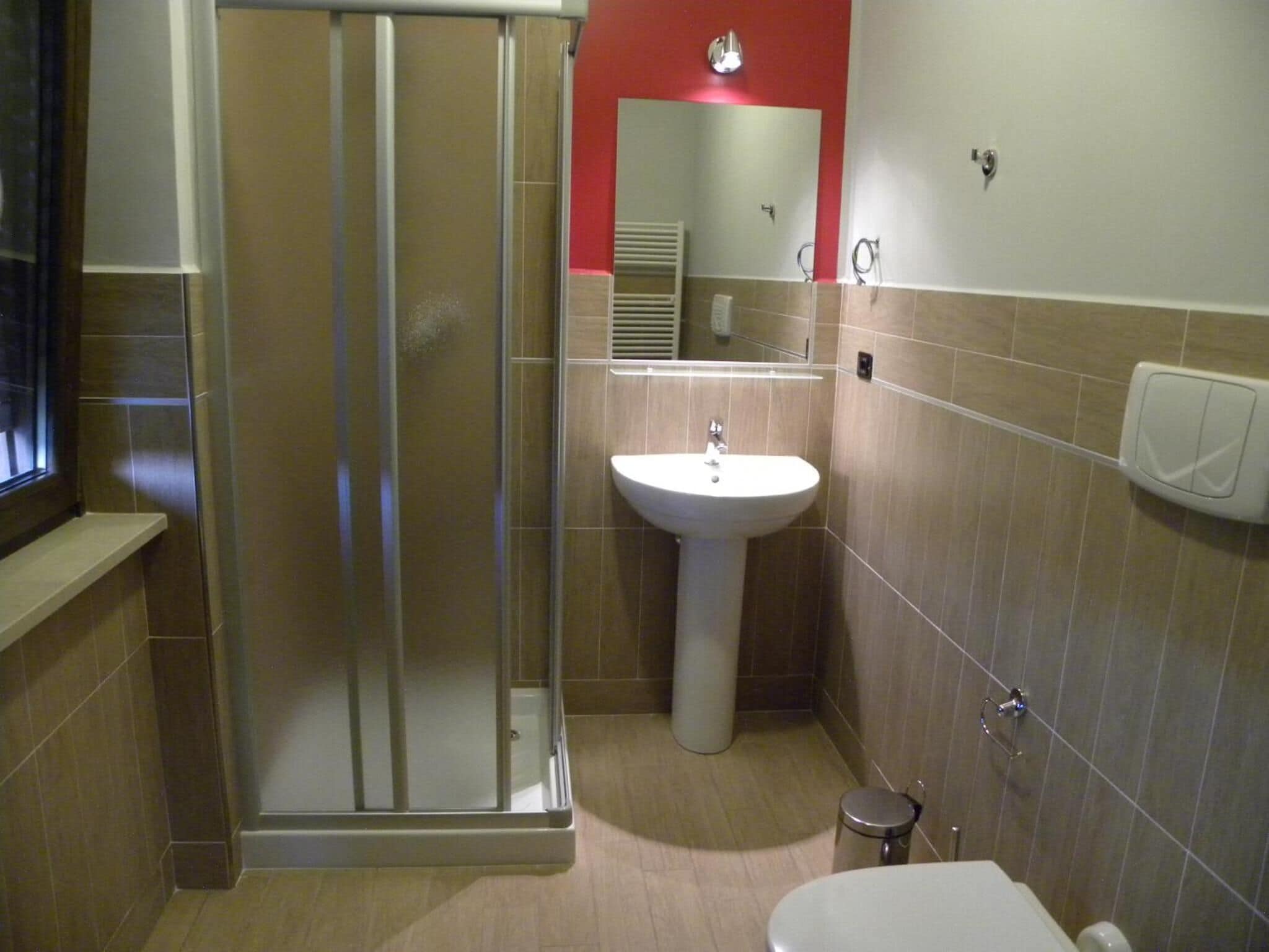A bathroom with a shower, sink, toilet, and a mirror.