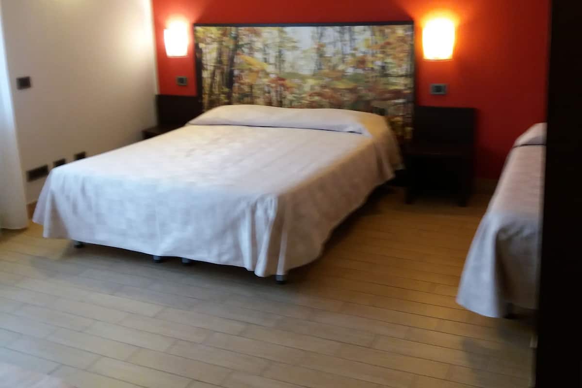 Un dormitorio con una cama, dos mesitas de noche y un cuadro colgado en la pared.