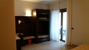 A hotel room with a bed, a desk with a chair, a wardrobe, and a window with curtains. - Affittacamere il Boscaiolo (L'Aquila)