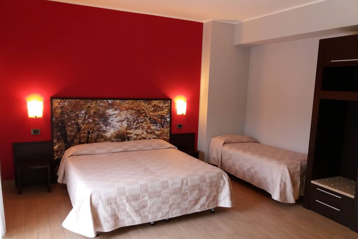 Habitación de hotel con una cama grande, dos mesitas de noche y un cabecero con una obra de arte de temática natural.