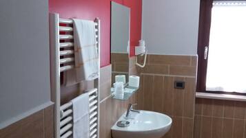A bathroom with a white sink, a mirror, a towel rack, and a window with curtains.
