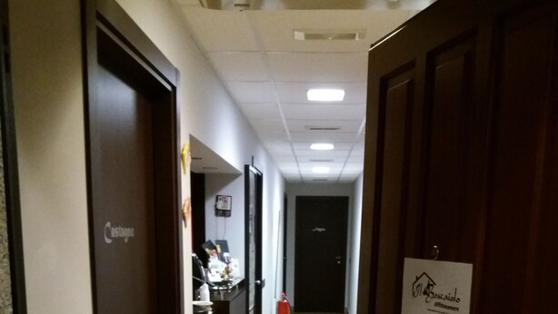 A hotel corridor with doors on both sides, a reception desk, and a fire extinguisher. - Affittacamere il Boscaiolo (L'Aquila)