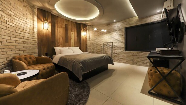 Ein modernes Schlafzimmer mit einem großen Bett, einer Couch, einem kleinen Tisch und einem Fernseher.