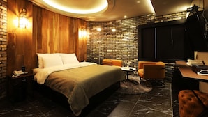 Ein modernes Hotelzimmer mit Backsteinwand, einem großen Bett, einem Schreibtisch und einer Sitzecke.