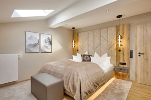 A modern bedroom with a skylight, a bed with a headboard, bedside tables, and a nightstand. - Hotel Alpenhof (Bad Wiessee)