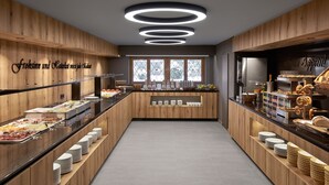 Een moderne buffetruimte met houten lambrisering, een centraal bedieningspunt en een raam met uitzicht op bomen.