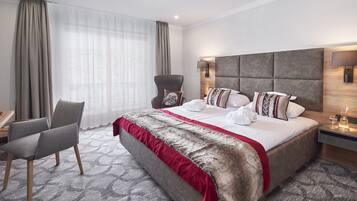 Ein modernes Hotelzimmer mit einem großen Bett, einem Sessel, einem Schreibtisch und einem Nachttisch mit Lampe.
