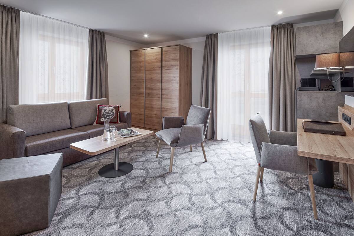 Ein modernes Wohnzimmer mit einer Couch, Sesseln, einem Couchtisch und einem Essbereich mit Tisch und Stühlen.