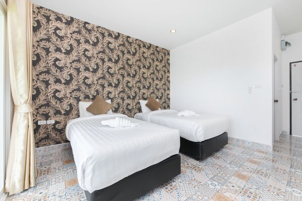 A hotel room with two beds, a patterned wallpaper, and a tiled floor. - Oasis Hiso Hotel (Lop Buri)