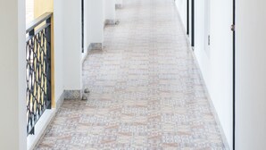 A long corridor with numbered doors, a fire extinguisher, and a fire alarm on the wall. - Oasis Hiso Hotel (Lop Buri)