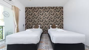 Une chambre d’hôtel avec deux lits, un papier peint à motifs, un sol carrelé et un balcon avec vue.