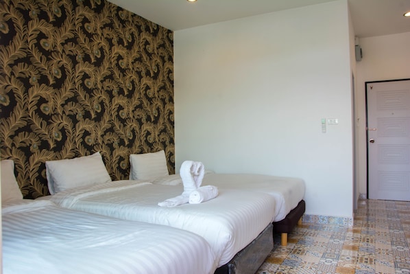 A hotel room with two beds, a patterned wallpaper on one wall, and a tiled floor. - Oasis Hiso Hotel (Lop Buri)