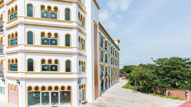 A multi-story hotel with a white facade, multiple balconies, and a clear sky. - Oasis Hiso Hotel (Lop Buri)