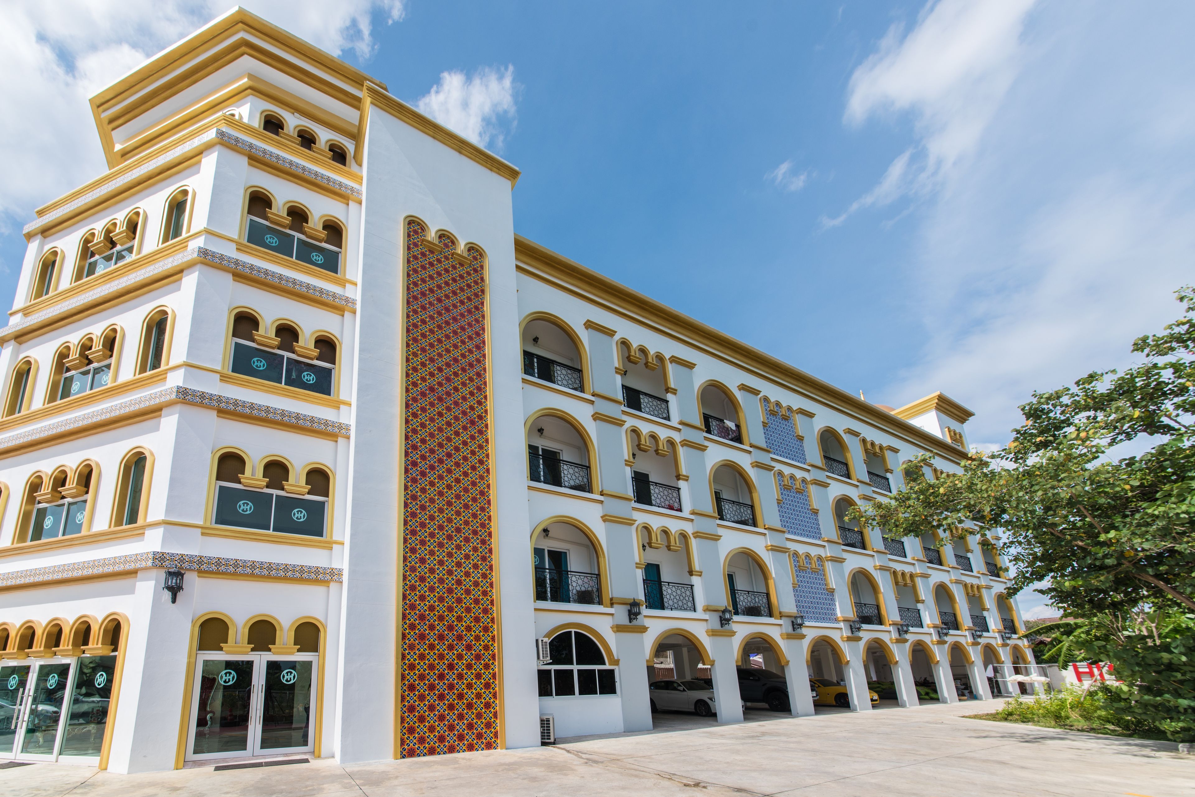 A multi-story hotel with a white facade, yellow trim, and arched windows.