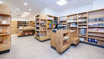 Una tienda con estanterías de madera llenas de diversos productos, un mostrador de caja y un suelo de baldosas.