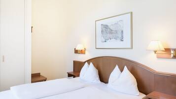 Una habitación de hotel con una cama, dos mesitas de noche y una lámpara de pared.