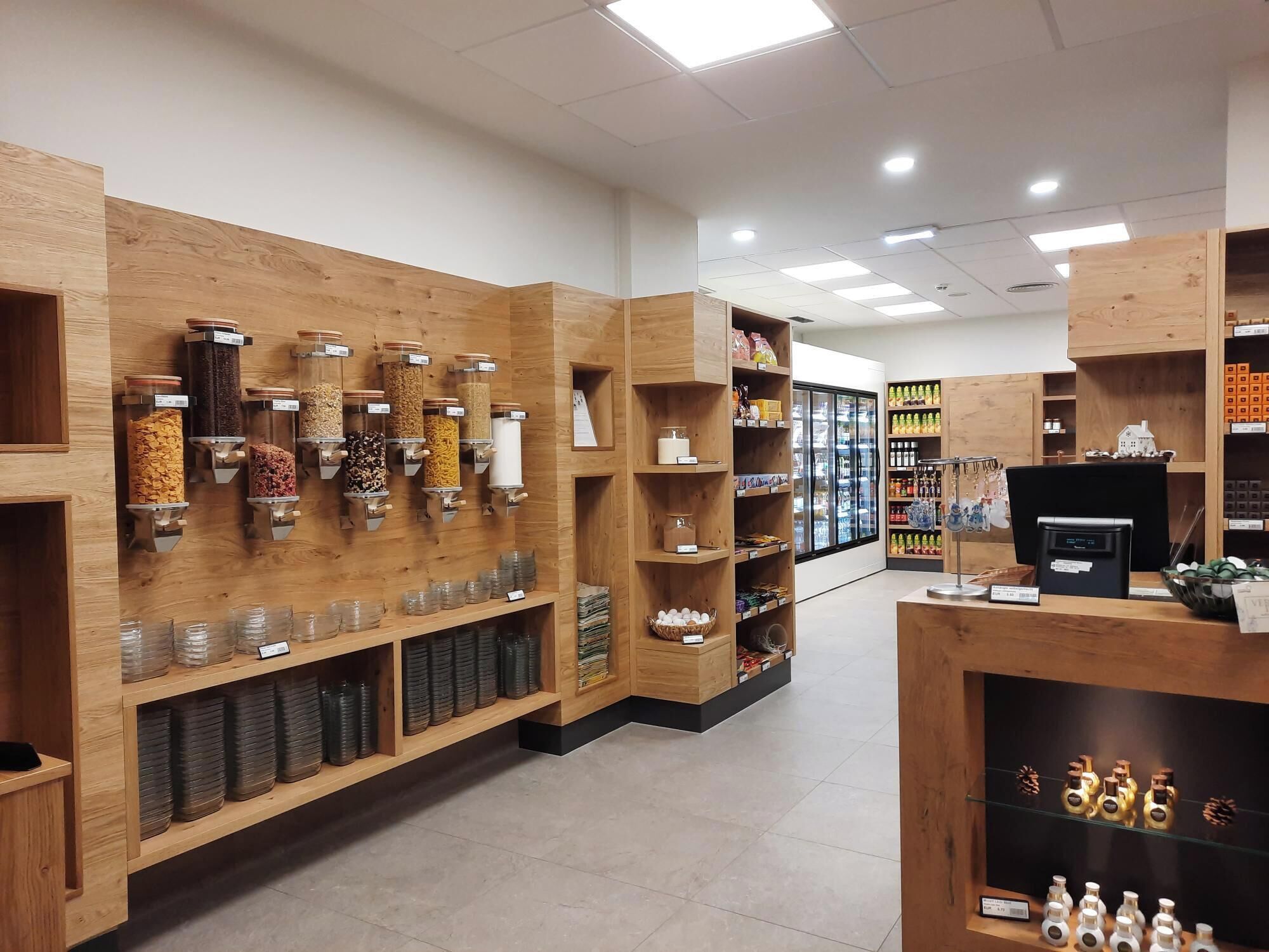 A store interior with wooden shelves, jars, and a refrigerated display.