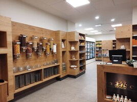 A store interior with wooden shelves, jars, and a refrigerated display.