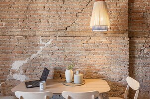 Un muro di mattoni rustico con un tavolo di legno, un laptop e due vasi con piante.
