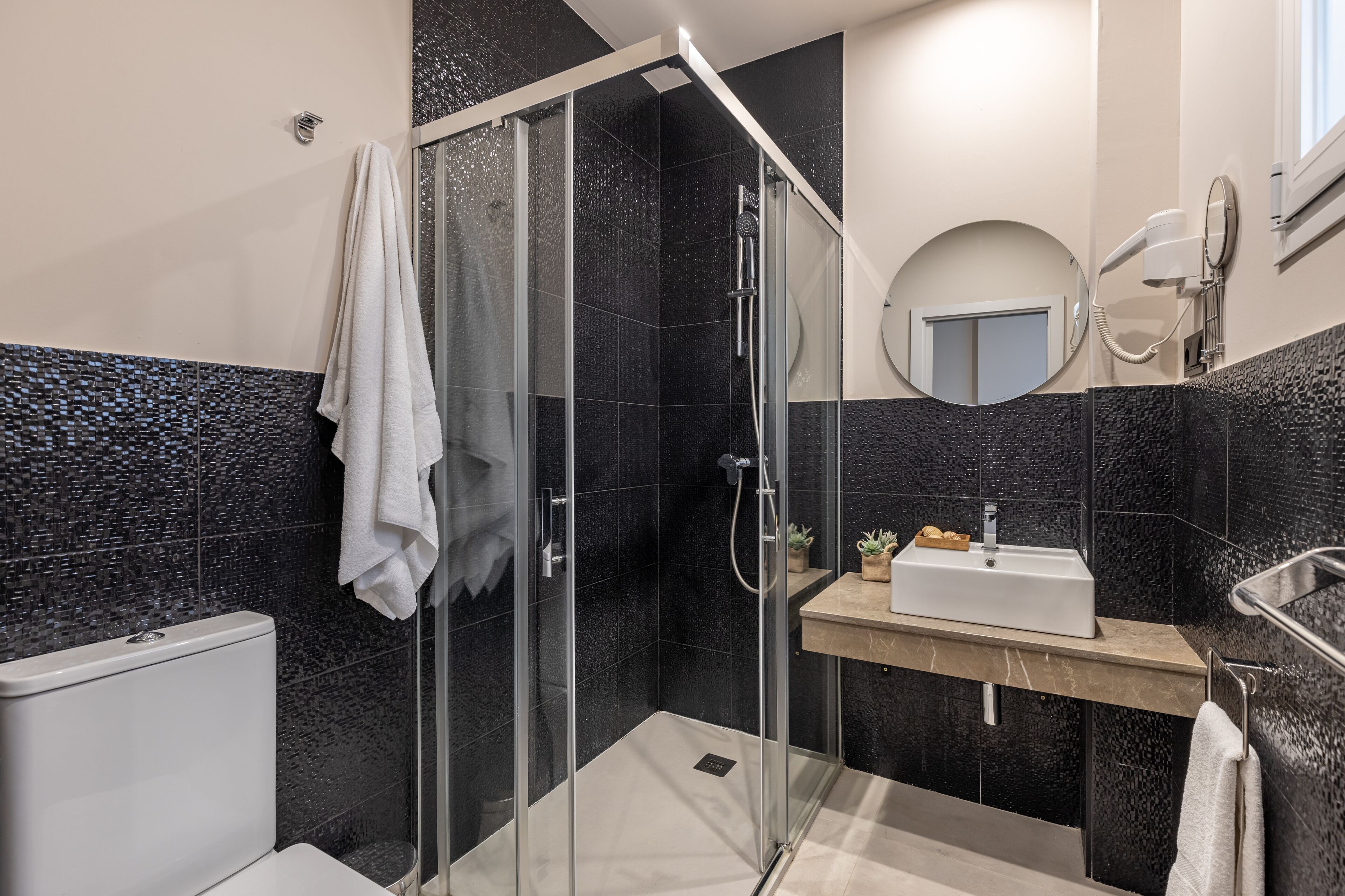 Une salle de bain moderne avec une douche à parois de verre, un lavabo blanc et un miroir.