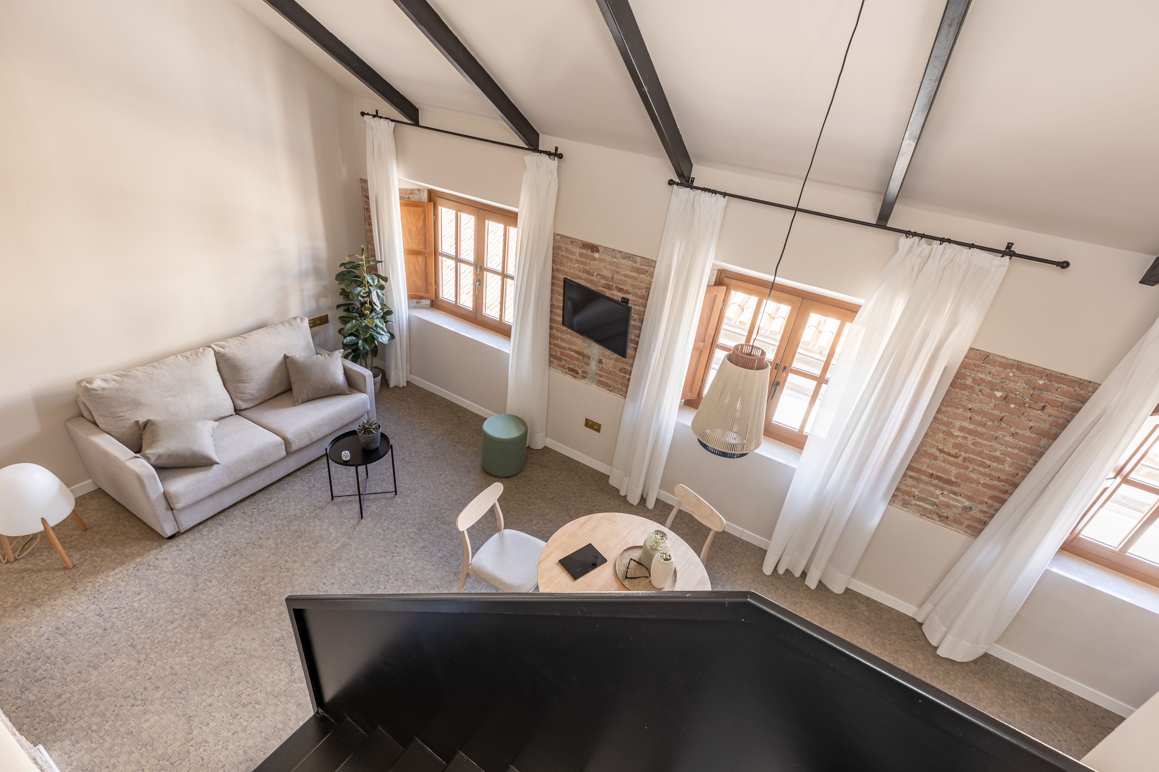 Een moderne woonkamer met een bank, een bijzettafeltje en een aan een bakstenen muur bevestigde televisie.
