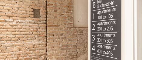 Une pancarte indiquant les numéros des appartements, de 101 à 405, dans un immeuble dont le mur de fond est en briques.