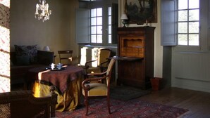A room with a sofa, chairs, a table, a chandelier, and a large window with a view. - Manoir du Plessis au Bois (Vauciennes)