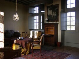 Quarto com sofá, cadeiras, mesa, lustre e uma grande janela com vista.