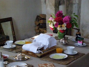 A dining table set with plates, cups, a vase of flowers, and a teapot. - Manoir du Plessis au Bois (Vauciennes)