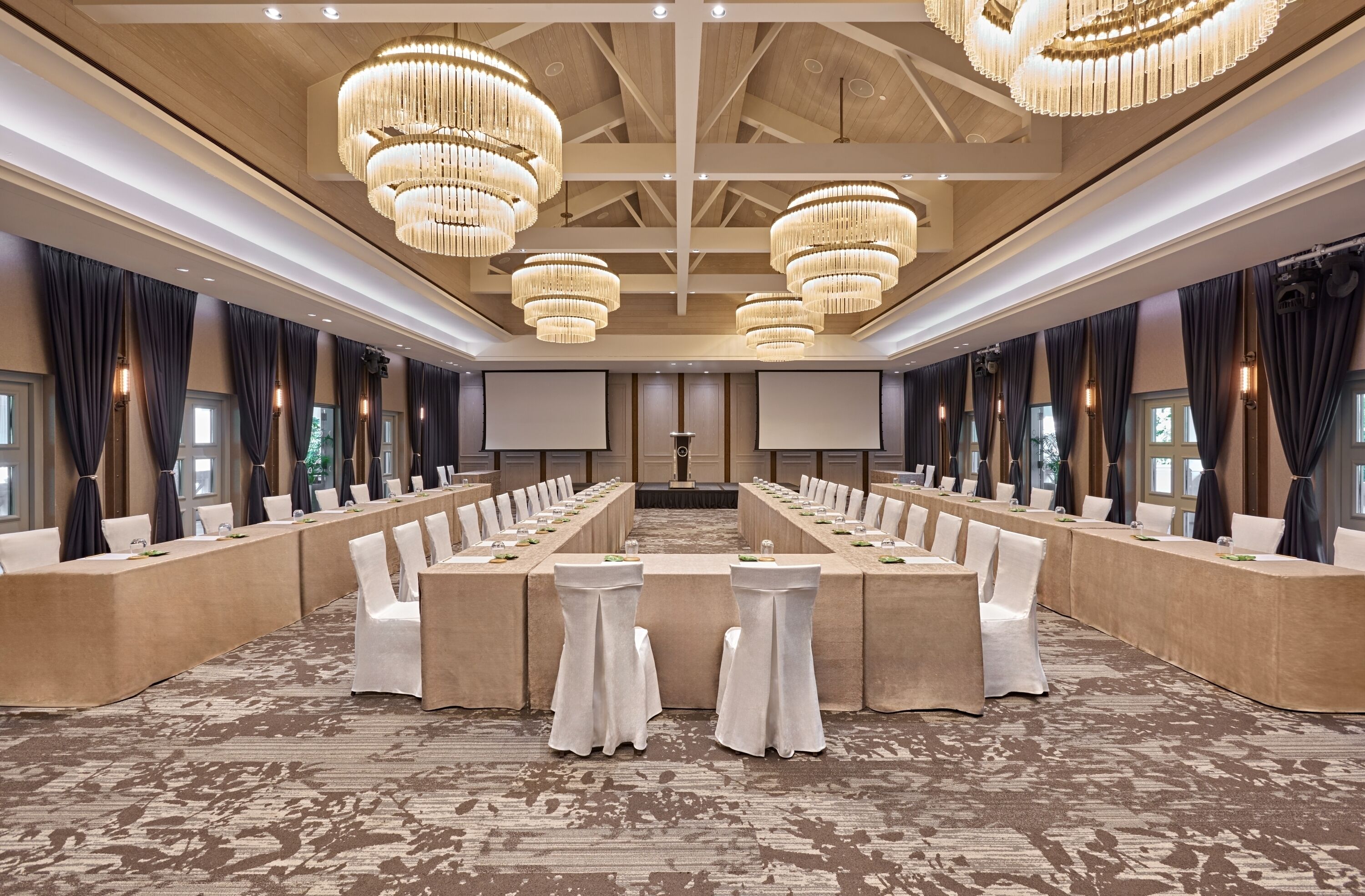 Un salón de conferencias con una larga mesa, sillas blancas y grandes candelabros.