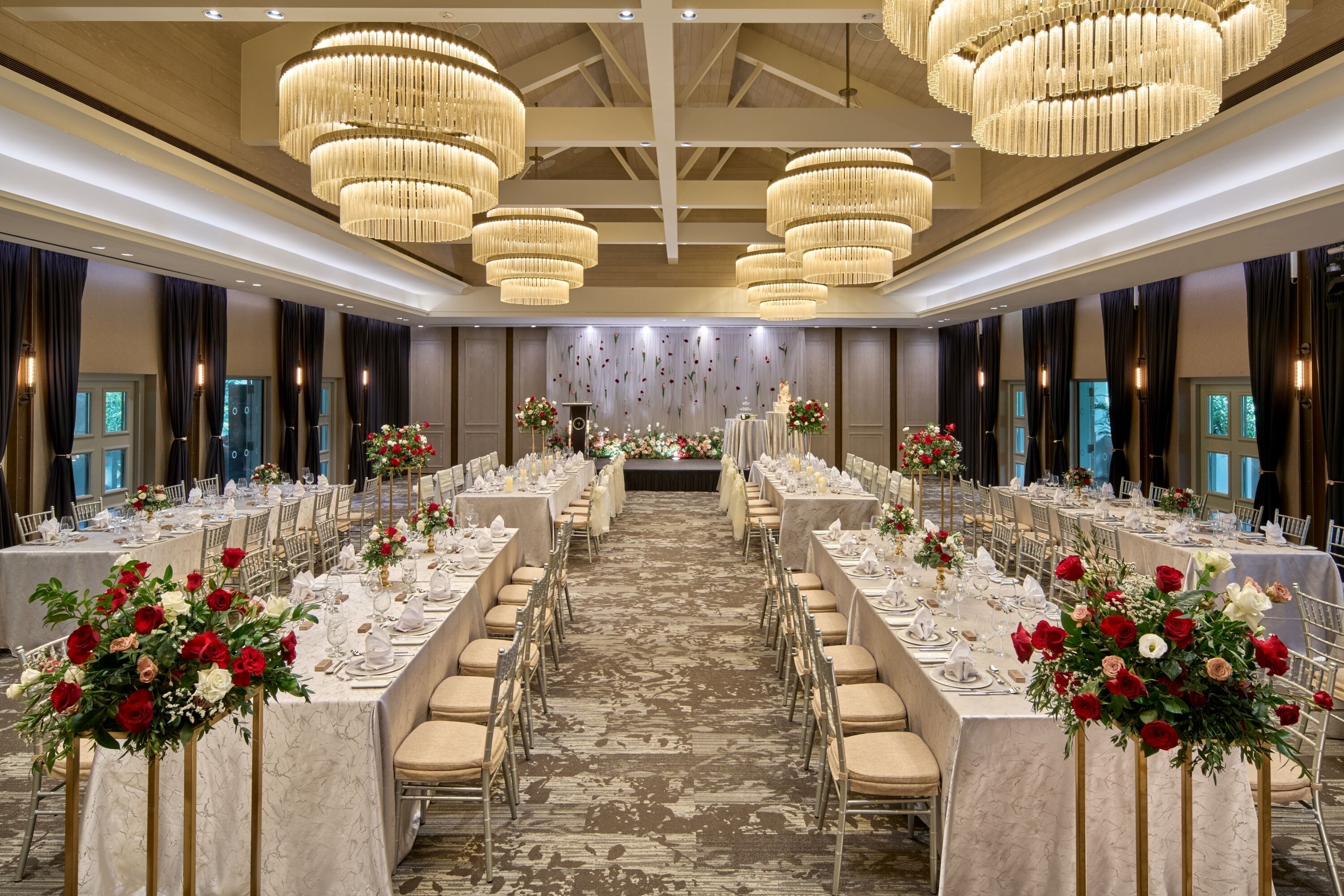A banquet hall with long tables, chandeliers, and floral centerpieces.