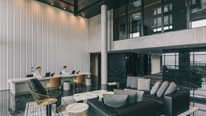 Un vestíbulo moderno con mostrador de recepción, zona de estar y ventanas amplias.
