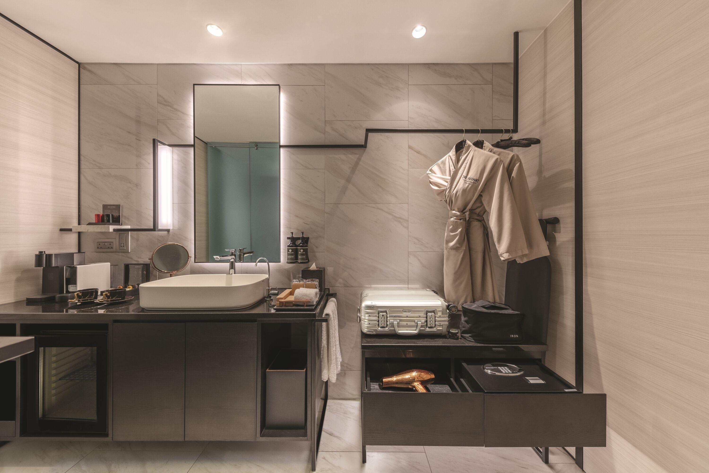 A modern bathroom with a large mirror, a sink, a vanity, and a robe hanging on a rack.